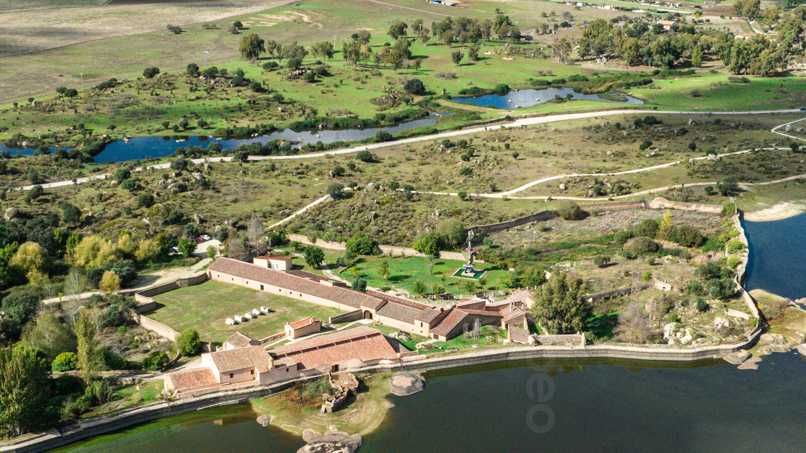 Dehesa extremeña y embalse vistos desde el aire, con una finca junto a la lámina de agua